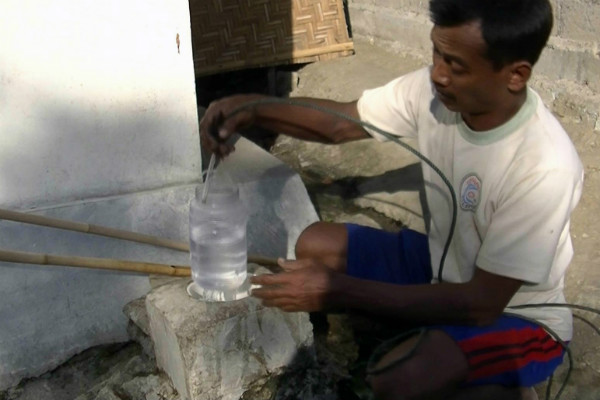 Warga Desa Mertelu mengambil air dari bekas sumur bor.