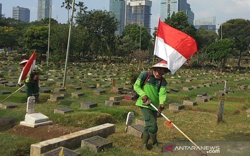 Petugas TPU Pangkas Rumput Permakaman Sambil Gendong Bendera Merah Putih
