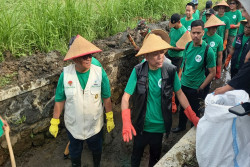 Wamensos Agus Jabo Masuk ke Selokan Bersihkan Sampah di Nanggulan Kulonprogo